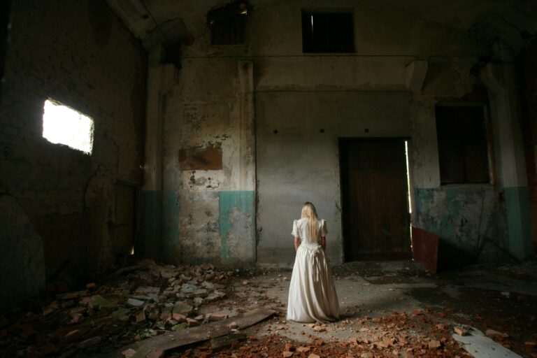 Woman in a white vintage dress standing in an abandoned, crumbling building