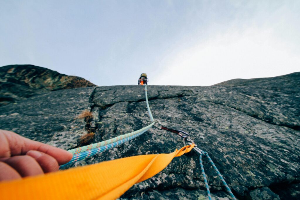 A climber scaling a steep rock face using safety ropes, symbolizing the thrilling journey of action and adventure audiobooks.