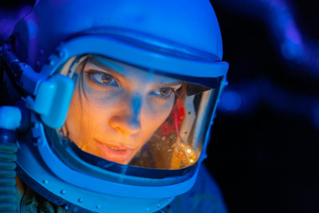 Close-up of a woman in a futuristic space helmet, bathed in blue and orange light, symbolizing science fiction exploration.