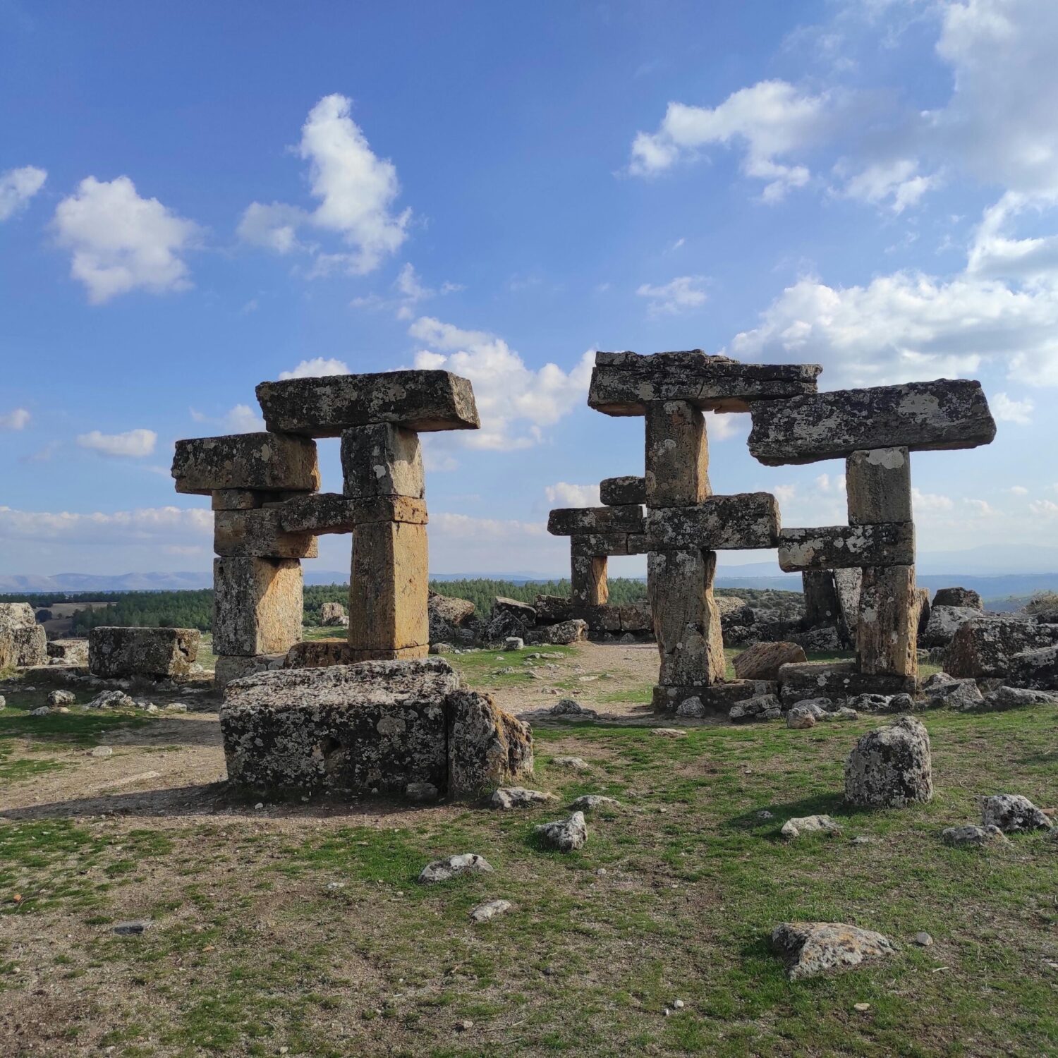 Ancient stone structures under a bright blue sky, resembling the ruins of a lost civilization in a vast open landscape.